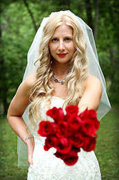 Sassy blonde Bride holds out her red roses