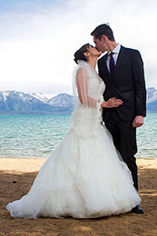 Bride and groom kiss on the beach of Lake Tahoe