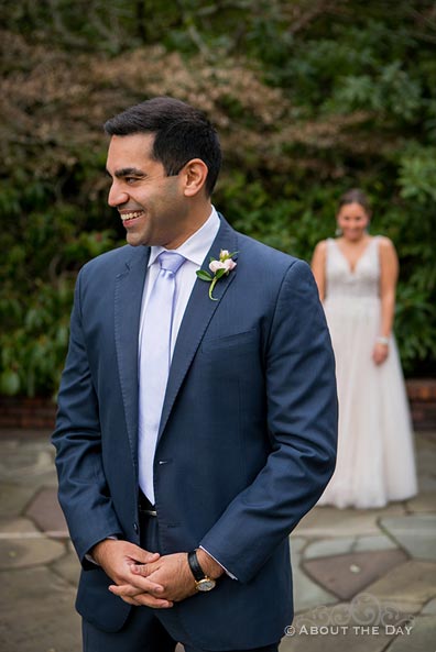 Groom laughs while Bride comes up behind him during their first look