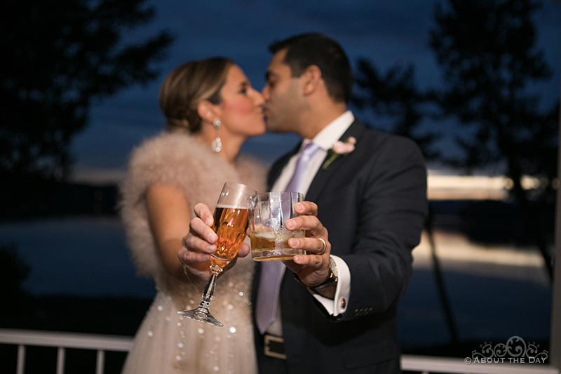 Heather and Naveed kiss with their wedding drinks